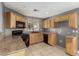 Bright kitchen featuring wood cabinetry, black appliances, tile flooring, and plenty of counter space at 8699 Grand Sequoia St, Las Vegas, NV 89139