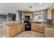 Functional kitchen showcasing wooden cabinets, tile floors, black appliances, and granite countertops at 8699 Grand Sequoia St, Las Vegas, NV 89139