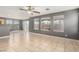 Open living area featuring tile flooring, a ceiling fan, and large windows overlooking the backyard at 8699 Grand Sequoia St, Las Vegas, NV 89139