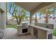 Outdoor kitchen and bar with stainless steel grill and fridge overlooking the backyard and landscaping at 8800 Las Olivas Ave, Las Vegas, NV 89147