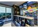 Modern bar area featuring custom lighting, stone countertops, display shelving, and neon decor with sliding glass doors to patio at 10605 Harvest Green Way, Las Vegas, NV 89135