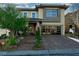 Two-story home featuring a glass garage door and a welcoming front porch with manicured landscaping and a paver driveway at 10605 Harvest Green Way, Las Vegas, NV 89135