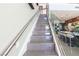 Bright, tiled staircase with glass railing leads to the upper level, bathed in natural light from nearby windows at 10605 Harvest Green Way, Las Vegas, NV 89135