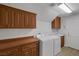 Bright laundry room with wooden cabinets, white washer and dryer, and a utility sink at 11158 Antonine Wall Ct, Las Vegas, NV 89141