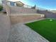 Landscaped backyard features artificial turf bordered by rock and is tiered with retaining walls for added dimension at 145 Medianoche St, Las Vegas, NV 89138