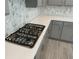 Gas range and white quartz counters accentuate the gray cabinets and geometric backsplash in the kitchen at 145 Medianoche St, Las Vegas, NV 89138