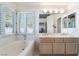 Bright bathroom featuring a soaking tub, double vanity, and plantation shutters at 2045 Summit Pointe Dr, Las Vegas, NV 89117