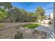 Landscaped backyard featuring a well-kept lawn, patio seating, and lush plant life at 23 Antero Dr, Henderson, NV 89074