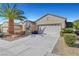 A single-story home showcasing desert landscaping, a palm tree and two-car garage under a blue sky at 2520 Eclipsing Stars Dr, Henderson, NV 89044