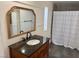 Bathroom features dark vanity with sink, large gold-framed mirror, and shower with decorative curtain at 325 Ron Ave, Logandale, NV 89021