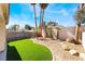 Landscaped backyard featuring rocks, artificial turf, and tropical palm trees at 4451 Tomer Ln, Las Vegas, NV 89121