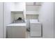 A clean laundry room featuring a washer, a dryer, and white shelving units at 4451 Tomer Ln, Las Vegas, NV 89121