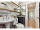 Well-lit bathroom with a large mirror, pedestal sink, wood-look accent wall, and tile flooring at 478 S Water St, Henderson, NV 89015