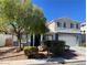 Two-story home with neutral paint scheme, manicured landscaping, mature tree, and an attached two-car garage at 6103 Harvest Dance St, North Las Vegas, NV 89031