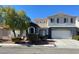 Two-story home with neutral paint scheme, manicured landscaping, mature tree, and an attached two-car garage at 6103 Harvest Dance St, North Las Vegas, NV 89031