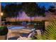 Illuminated backyard spa with lounge chairs and mature trees at dusk at 7607 Boca Raton Dr, Las Vegas, NV 89113