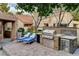 Beautiful outdoor kitchen with stainless steel grill, mini-fridge, granite countertops, and brick patio area at 7607 Boca Raton Dr, Las Vegas, NV 89113