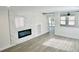 Bright living room features a modern fireplace and wood floors with a view of the stairs and backyard at 7808 Wavering Pine Dr, Las Vegas, NV 89143