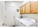 Functional laundry room with cabinets above the modern washer and dryer for ample storage at 7828 Homing Pigeon St, North Las Vegas, NV 89084