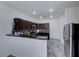 Modern kitchen featuring dark cabinetry, granite countertops, stainless steel appliances, and a stylish backsplash at 840 Sheerwater Ave, Henderson, NV 89052