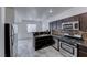 Modern kitchen showcasing stainless steel appliances, dark cabinets, and a tile backsplash, with a view to the living room at 840 Sheerwater Ave, Henderson, NV 89052