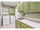 Bright laundry room with green cabinets, quartz countertops, and modern washer/dryer units at 9809 Gerald Ct, Las Vegas, NV 89134