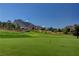 Expansive golf course with lush green grass, mountain views, and a blue flag on a sunny day at 9912 Woodhouse Dr, Las Vegas, NV 89134