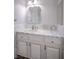 Bathroom featuring a scalloped mirror and marble countertops on white cabinets with detail at 1125 Via Canale Dr, Henderson, NV 89011