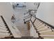 A beautiful staircase with white banisters leads down to a light-filled living space with gray floors and modern decor at 1921 Spyglass Dr, Henderson, NV 89074