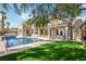 Lush backyard with a sparkling pool, manicured lawn, and mature trees at 2690 Grassy Spring Pl, Las Vegas, NV 89135