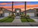 Beautiful two-story home featuring dual garages, a landscaped yard, and towering palm trees at sunset at 2690 Grassy Spring Pl, Las Vegas, NV 89135