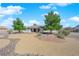 A well-maintained front yard featuring desert landscaping, stone pathways, and mature trees framing the home at 2901 S Dandelion St, Pahrump, NV 89048