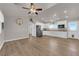 Open-concept living space with wood-look flooring, ceiling fan, and white kitchen cabinets at 2901 S Dandelion St, Pahrump, NV 89048