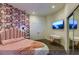 Bedroom featuring a mirrored closet, accent wallpaper, a pink bed, and modern lighting at 4712 Stavanger Ln, Las Vegas, NV 89147