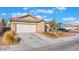 Welcoming single-story home with a two-car garage, desert landscaping, tile roof, and a paved driveway at 6061 Leaping Foal St, North Las Vegas, NV 89081