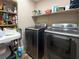 Efficient laundry room with modern washer and dryer units, and overhead shelving at 6627 Bristle Canyon Ave, Las Vegas, NV 89110