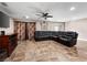 Spacious living room featuring tile flooring, ceiling fan, and a large leather sectional sofa at 6627 Bristle Canyon Ave, Las Vegas, NV 89110