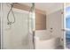Bright bathroom featuring a tiled shower, separate tub, and light fixtures at 7909 Fossil Creek Ln # 202, Las Vegas, NV 89145