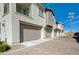 View of townhome garage exteriors with brick paved driveway and manicured shrubs at 8562 Insignia Ave # 102, Las Vegas, NV 89178