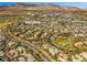 Wide aerial view of a residential community with mature landscaping, mountain views, and a golf course at 9616 Grand Isle Ln, Las Vegas, NV 89144