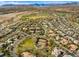 Wide aerial view of a residential community with mature landscaping, mountain views, and a golf course at 9616 Grand Isle Ln, Las Vegas, NV 89144