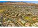 Wide aerial view of a residential community with mature landscaping, mountain views, and a golf course at 9616 Grand Isle Ln, Las Vegas, NV 89144