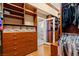 Spacious walk-in closet with custom wood cabinetry, shelving, drawers, and a convenient bathroom entry at 9616 Grand Isle Ln, Las Vegas, NV 89144