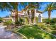 A picturesque home exterior, with a stone archway, verdant landscaping, and a well-manicured lawn at 9616 Grand Isle Ln, Las Vegas, NV 89144