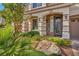 Elegant front entrance with stone accents, a covered porch, and lush landscaping at 9781 Arcadian Estate Ct, Las Vegas, NV 89141