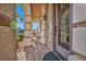 Charming front porch with brick flooring, stone pillars, and a cozy seating area at 9781 Arcadian Estate Ct, Las Vegas, NV 89141