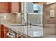 Close-up shot of a kitchen sink with granite countertops and wooden cabinets at 9781 Arcadian Estate Ct, Las Vegas, NV 89141
