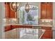 A close-up view of a kitchen area with stone countertops, stainless steel appliances and wooden cabinets at 9781 Arcadian Estate Ct, Las Vegas, NV 89141