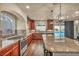 A well-lit kitchen featuring wooden cabinets, granite countertops, stainless steel appliances, and backyard views at 9781 Arcadian Estate Ct, Las Vegas, NV 89141