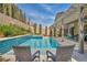 Sparkling blue pool and spa with patio featuring chairs and landscaping at 9781 Arcadian Estate Ct, Las Vegas, NV 89141